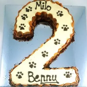 A cake with the number two and paw prints on it.