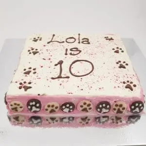 A cake with pink and brown paw prints on it.